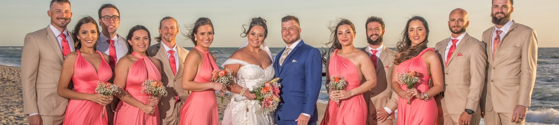 Wedding party on the beach — coral bridesmaids and blue groom